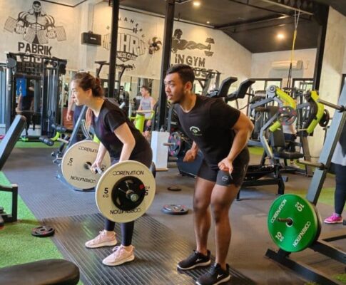 Pemula sedang melakukan latihan fitness di gym modern dengan program latihan full body